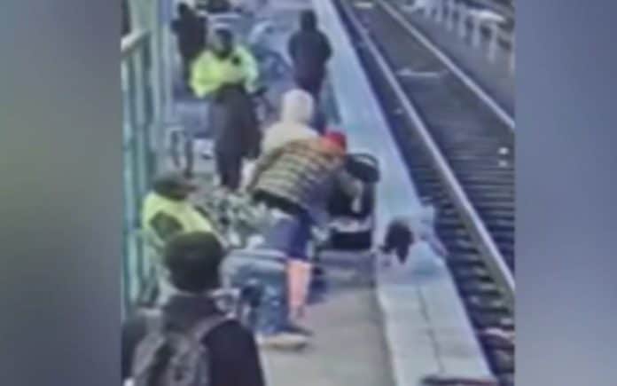 woman pushes a 3 year-old girl towards the train tracks